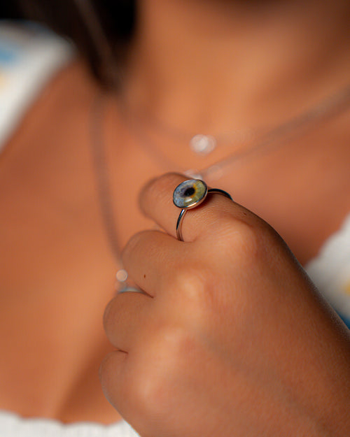 Close-up of a hand wearing a silver ring with a green gemstone.